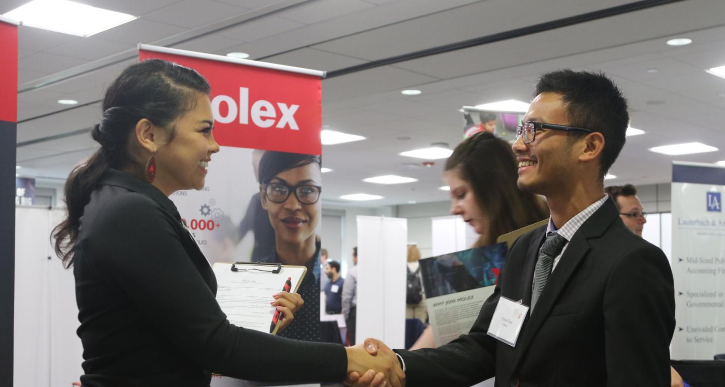 A student shakes hands with a potential employer for a chance at post-college careers.
