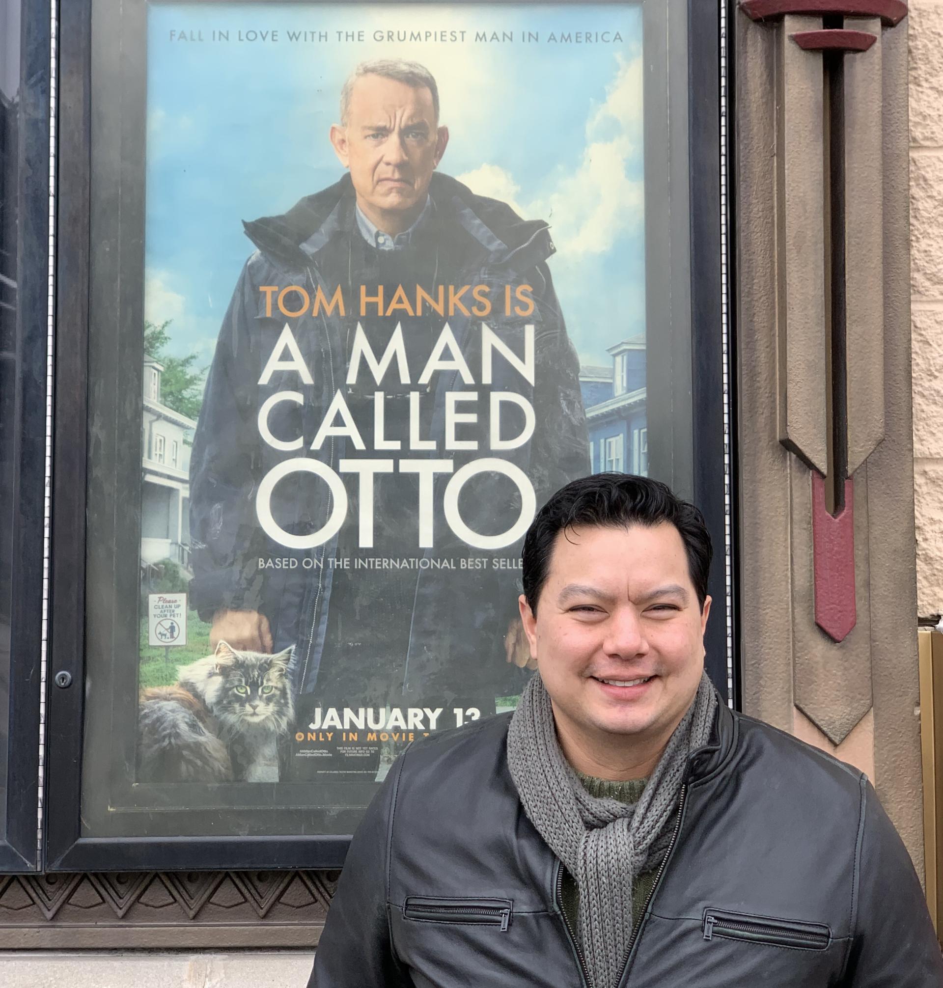 North Central College alumnus Peter Sipla poses in front of the poster for the movie "A Man Called Otto."