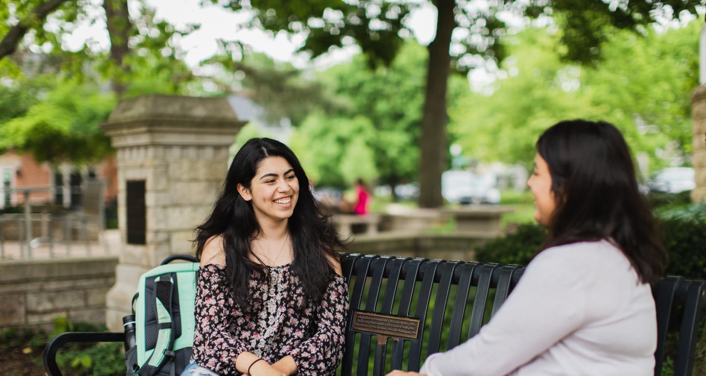 Two students talking on a campus bench