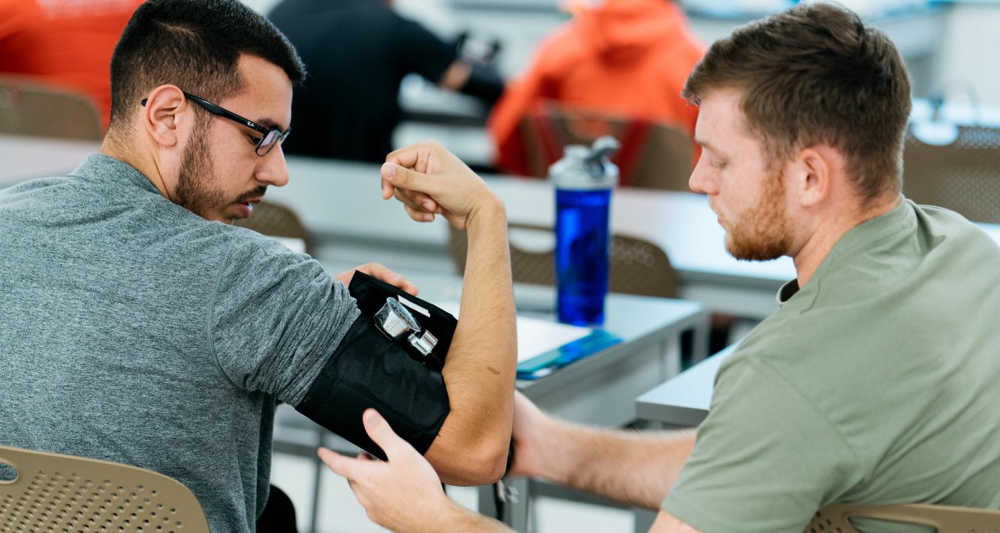 A student monitors a patient's heart rate.