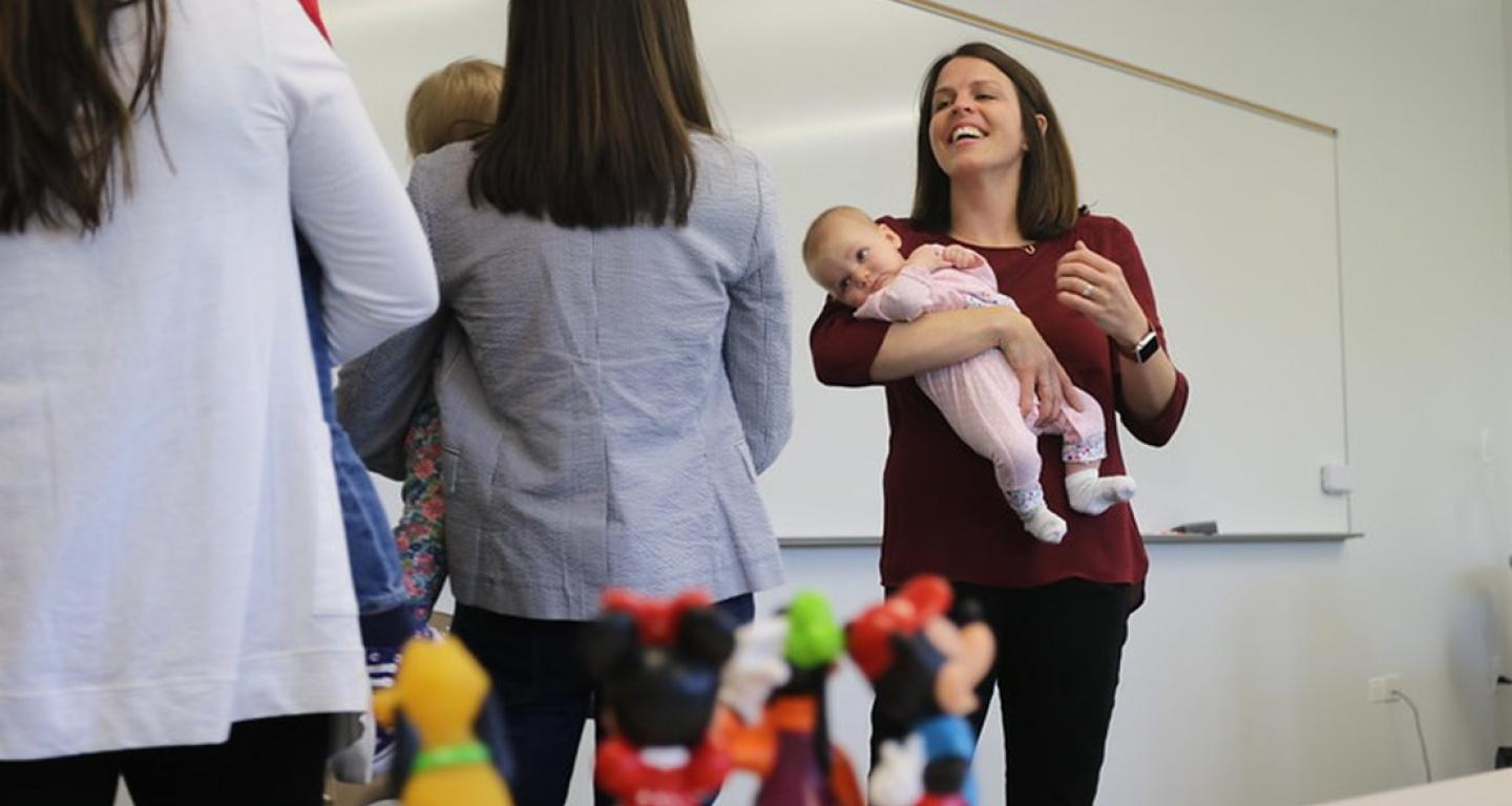 person holding baby in front of students