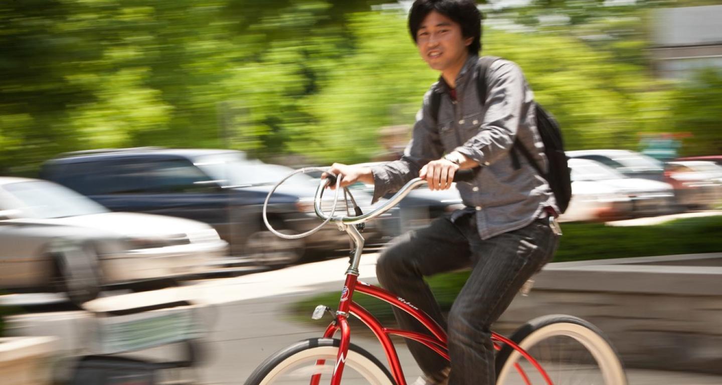 student riding a red bike outside