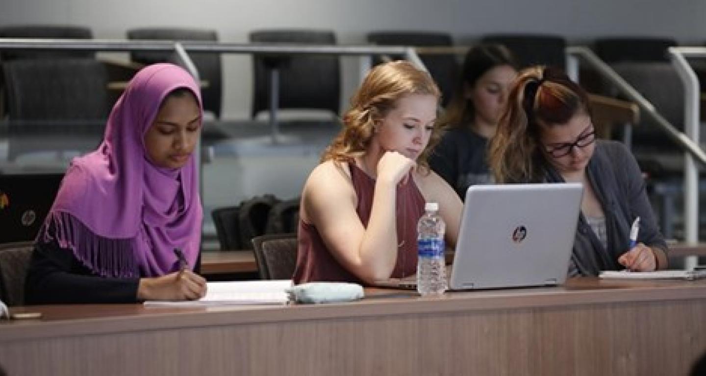 3 students taking notes during class