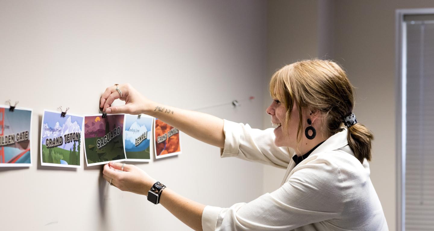 A North Central College graphic design student hangs up a project on the wall.