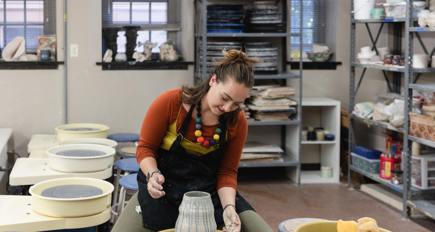 A North Central College art education student making pottery.