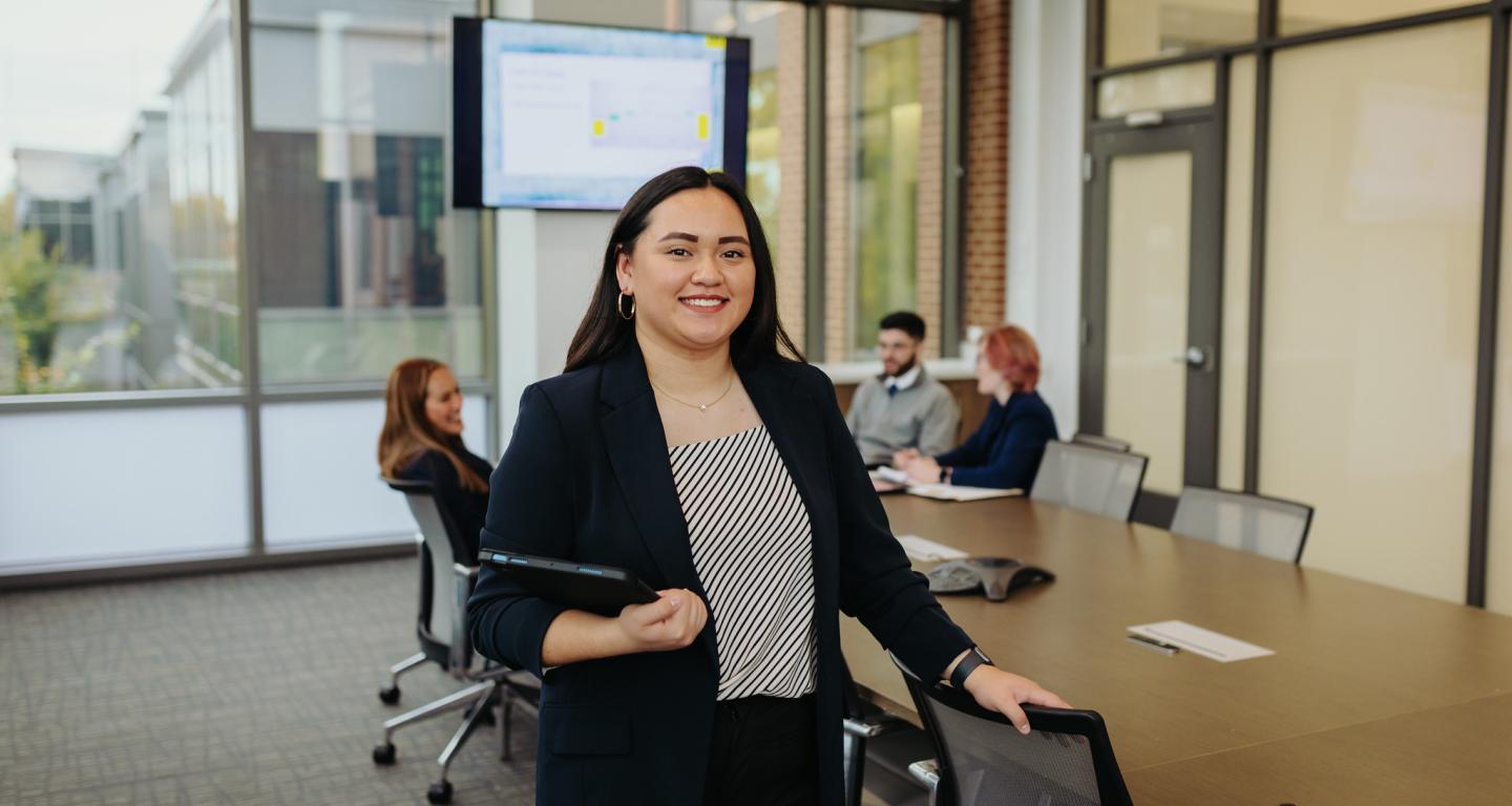 A photo of a business student in a board room on campus.