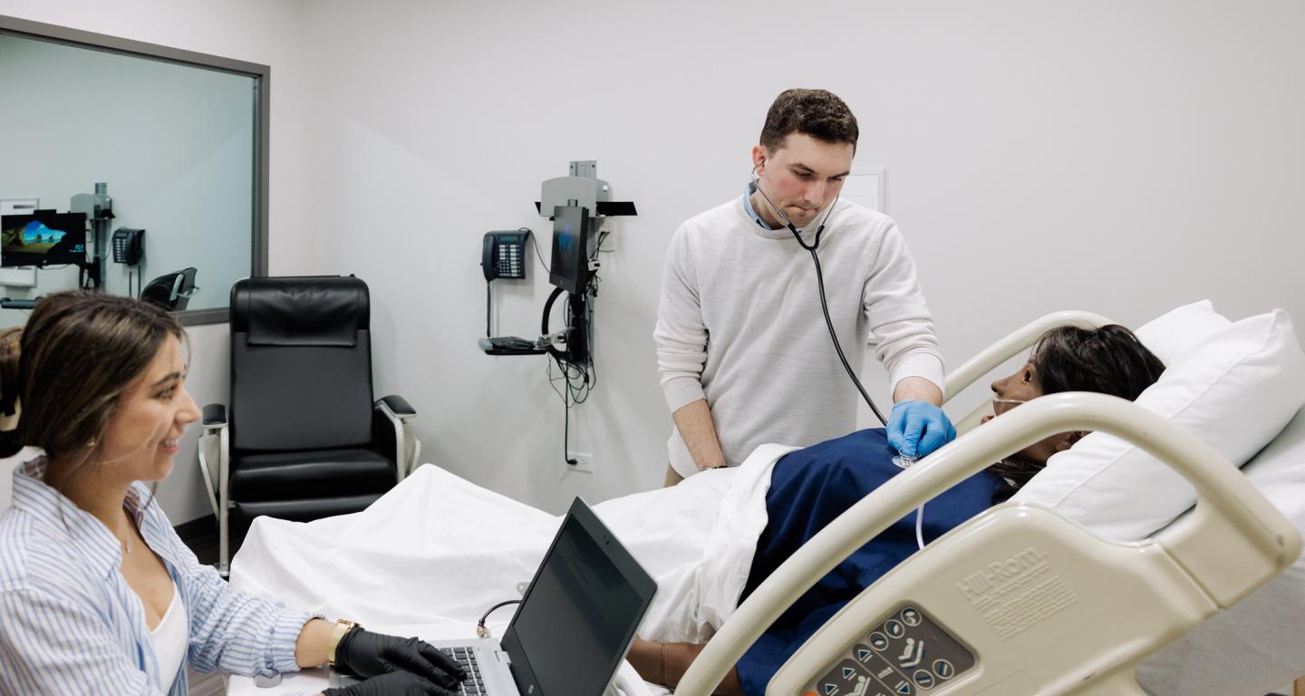 Two nursing students are working in a lab on campus.