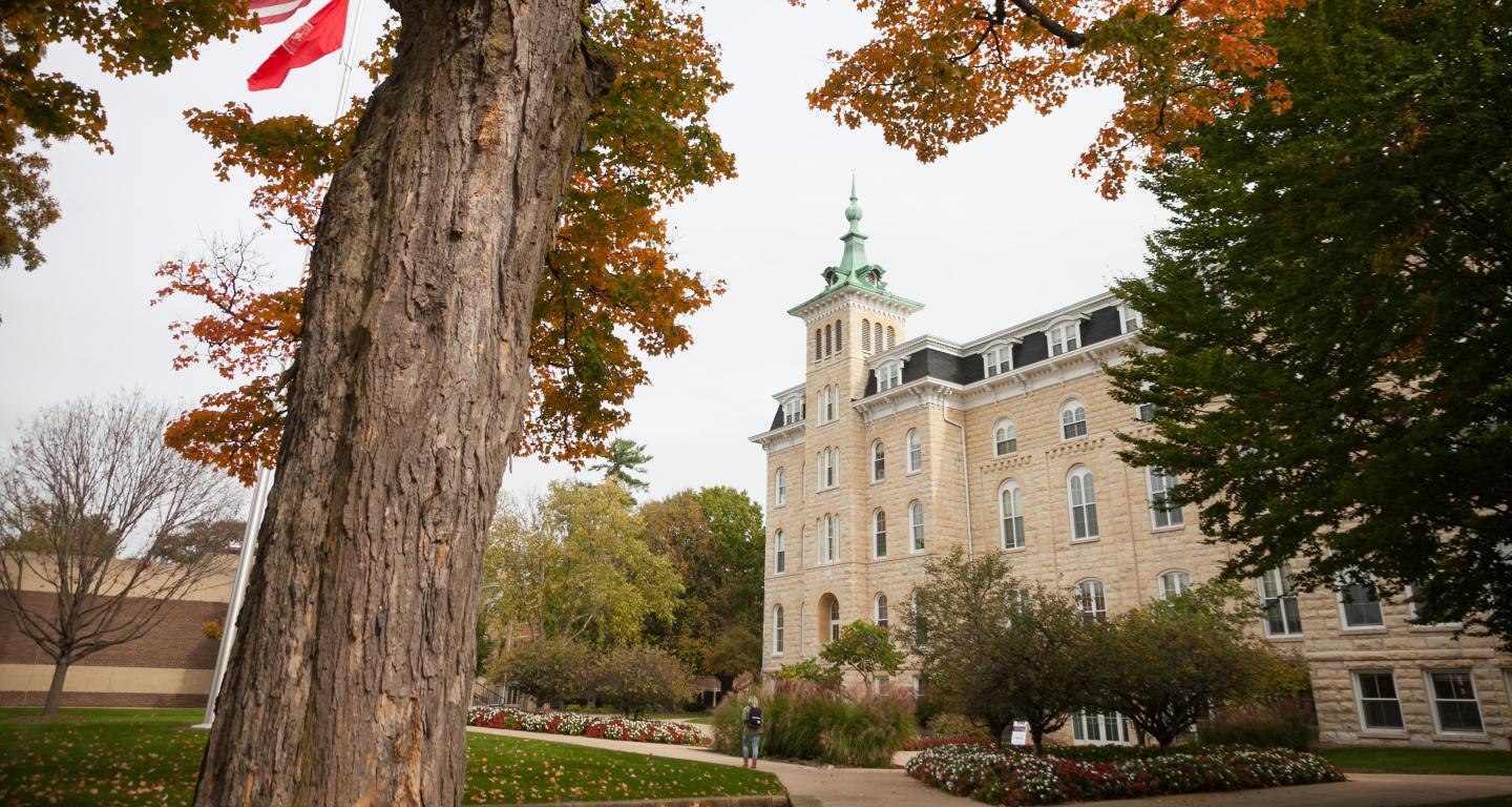 old main in the fall between some trees