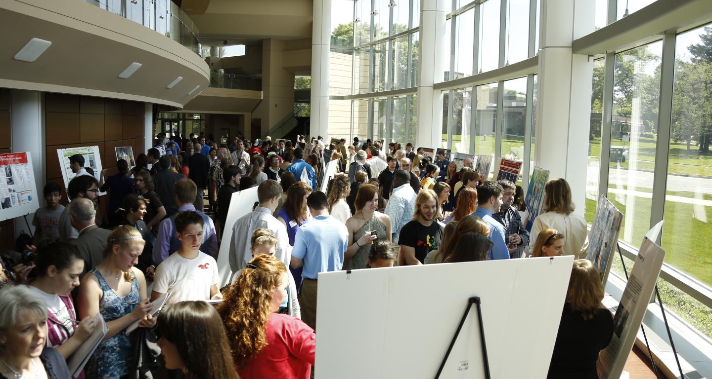 A group of visitors viewing posters at the annual Rall Symposium.