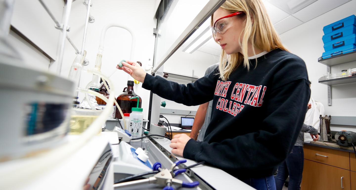 A student pouring a solution, studying one of the many types of chemistry.