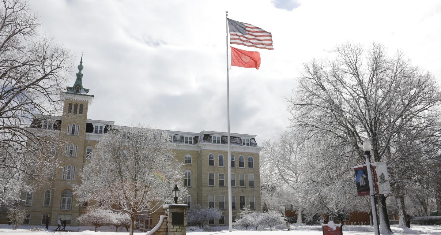 Old Main flying American Flag and College Flag in Winter