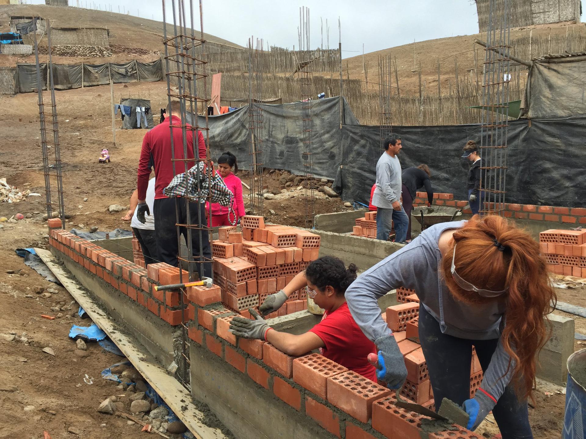 Maria Requena '18 and BREAKAWAY president Danielle McAuliff lays bricks for the home’s foundation in La Florida, Peru.