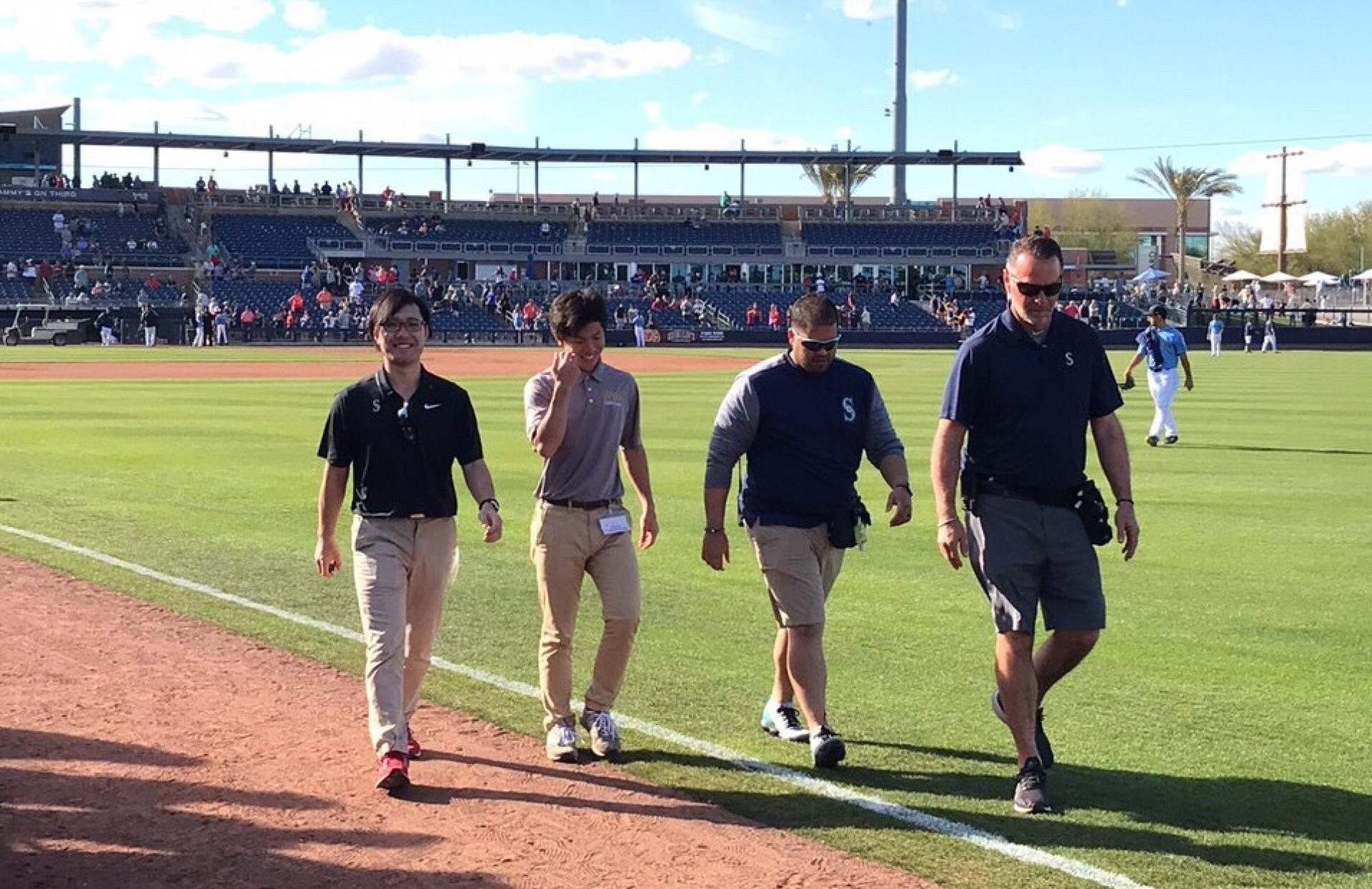 Shota Sato and Seattle Mariners' athletic trainers walk on the field