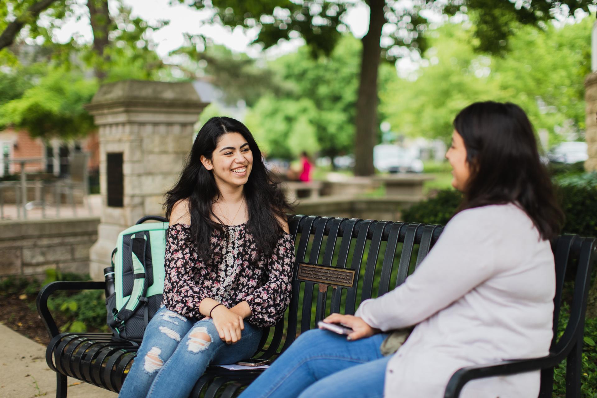 Two students talking on a campus bench