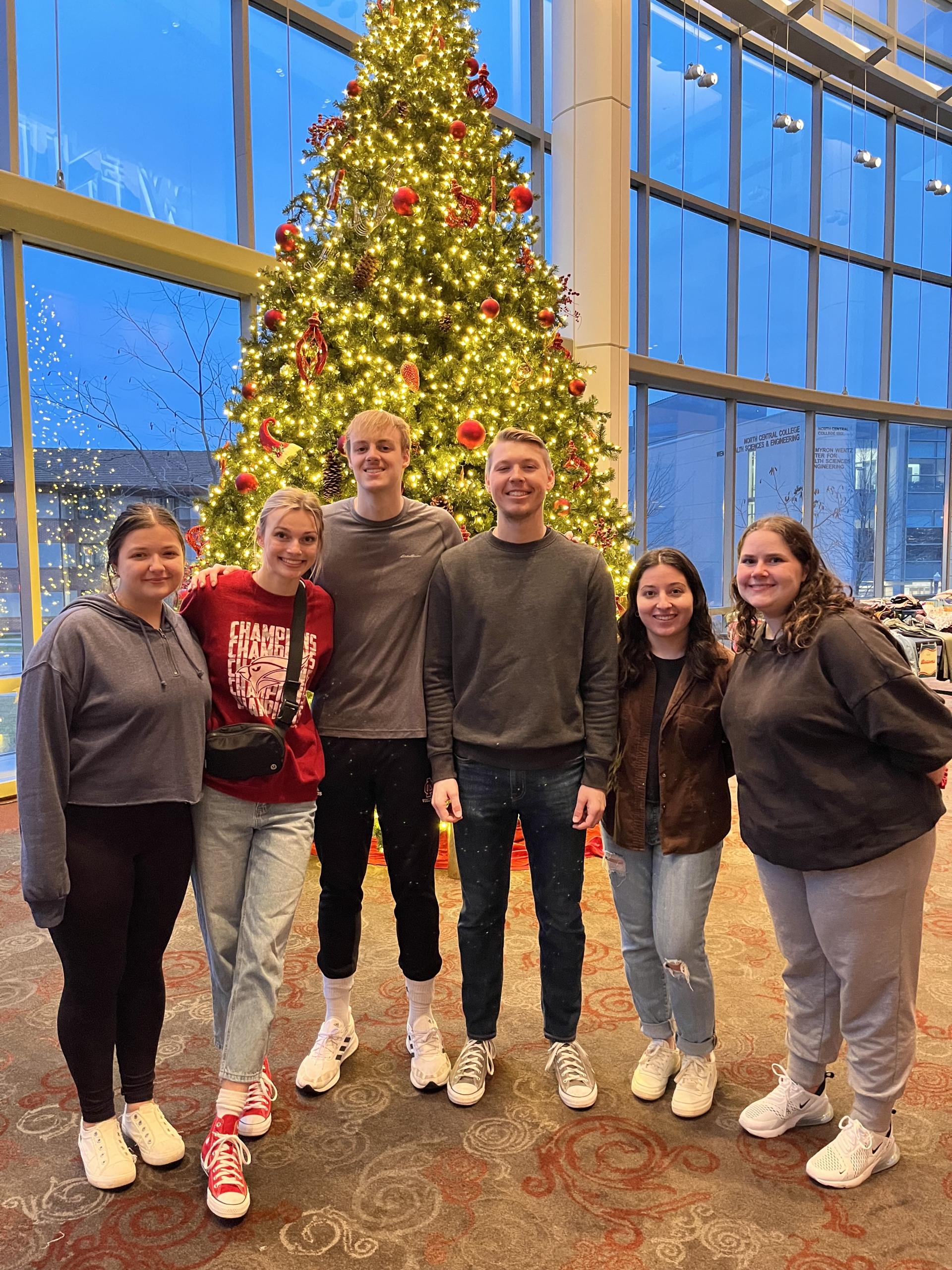 Carly Drake's marketing students in front of the Christmas tree during their clothing drive. 