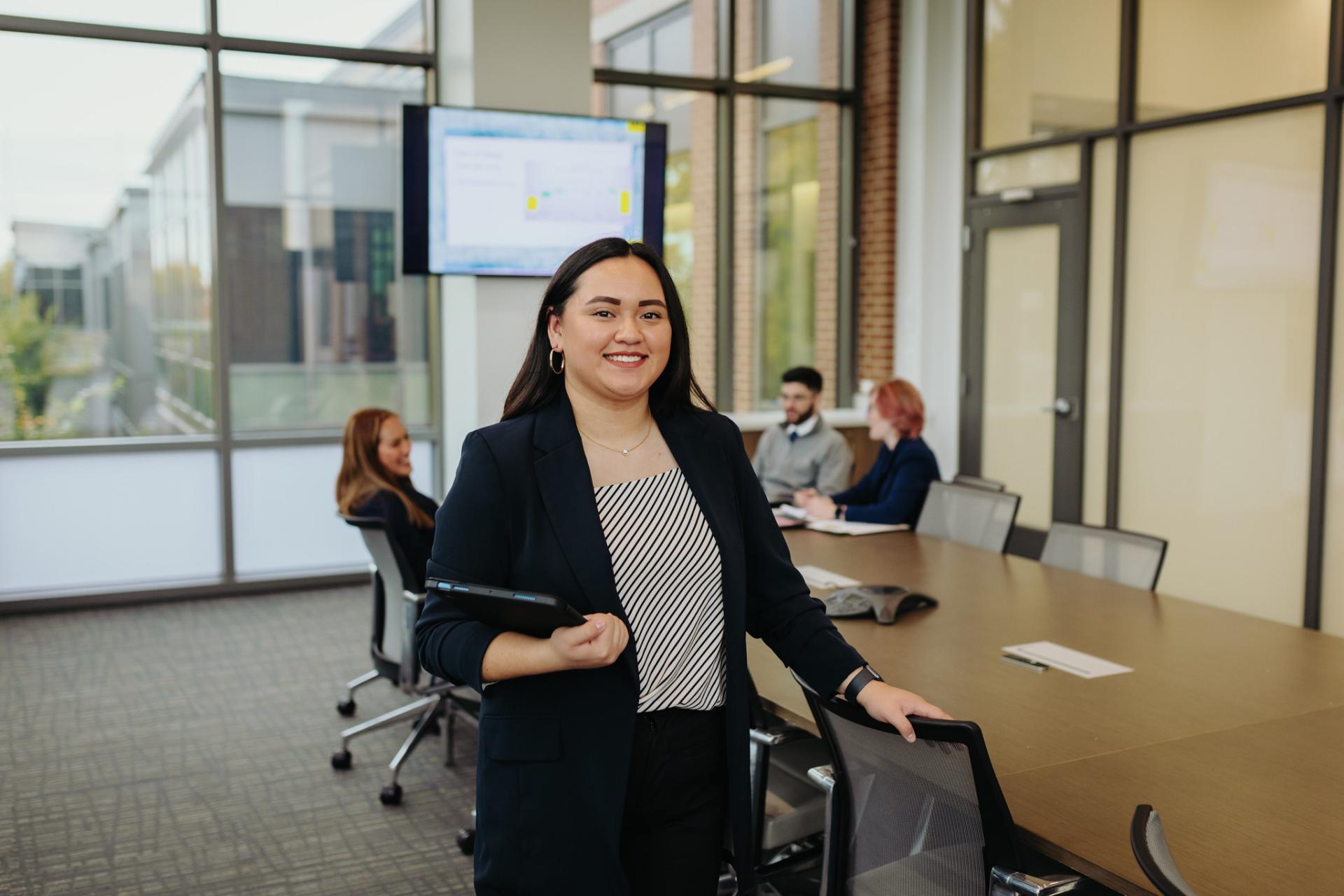 A photo of a business student in a board room on campus.