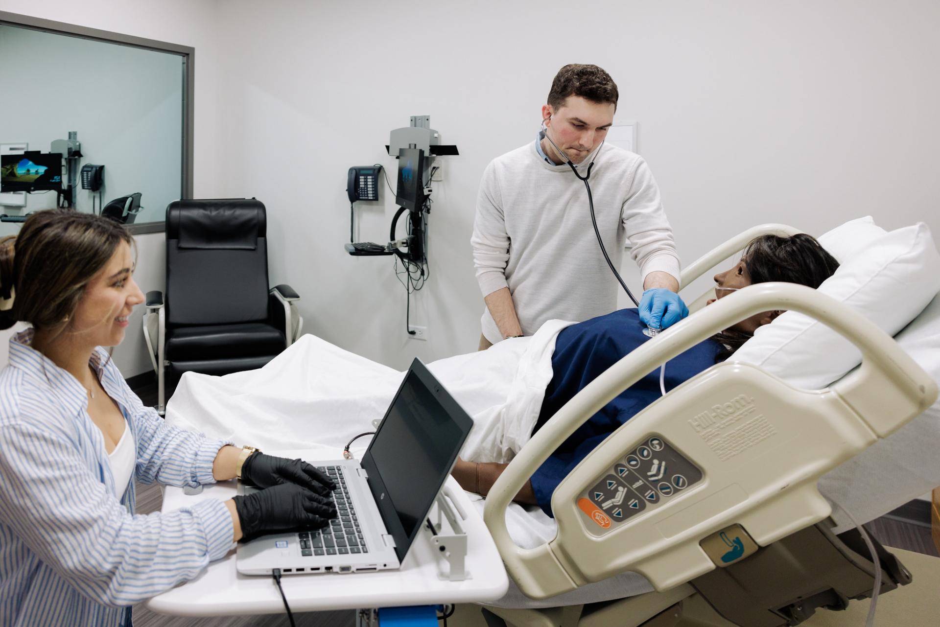 Two nursing students are working in a lab on campus.