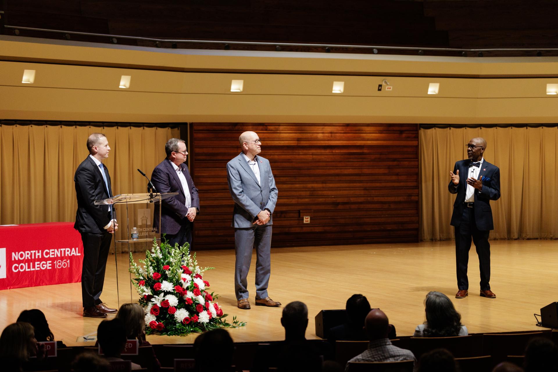 Dean David Green on stage with Thomas J. Paleka ’83, David E. Thomson, and President G-P.