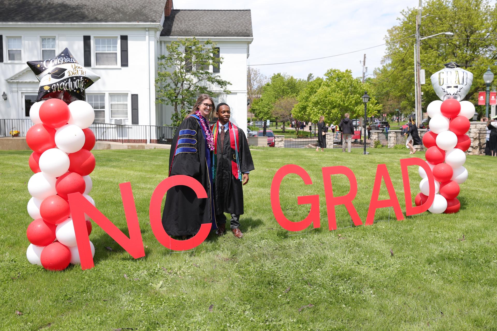 A professor and graduate are posing for a photo at Commencement.