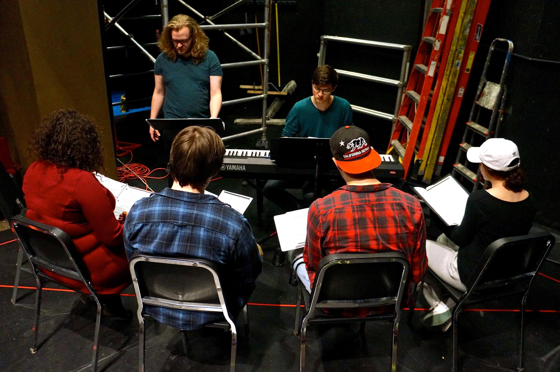 Students sitting in front of a keyboard rehearsing "I Love You, You're Perfect, Now Change."