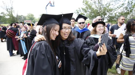 Professor and graduate taking selfie at commencement