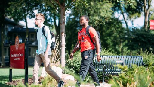 one student walking ahead of another student outside