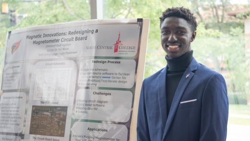 Emmanuel Boadi Agyekum ’26 is posing for a photo next to his research poster.