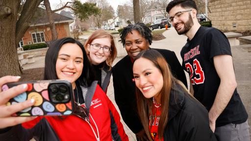 Four students are taking a selfie with President Thomas.