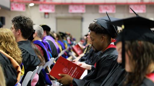 A photo of a graduate looking at the commencement program during the ceremony.