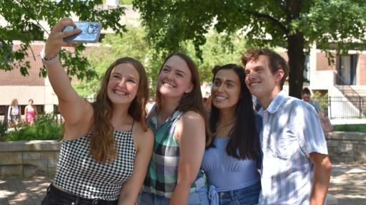 Four students taking a selfie outside on campus.
