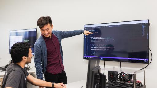 student pointing to code on monitor