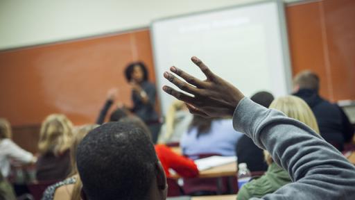 A student raising his hand to ask a question.