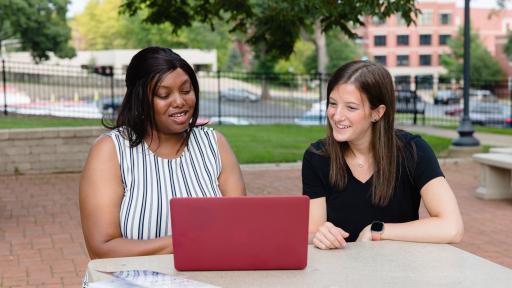 Students talking in front of a laptop