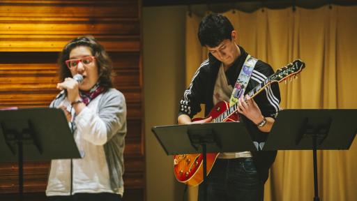 two students performing music on stage